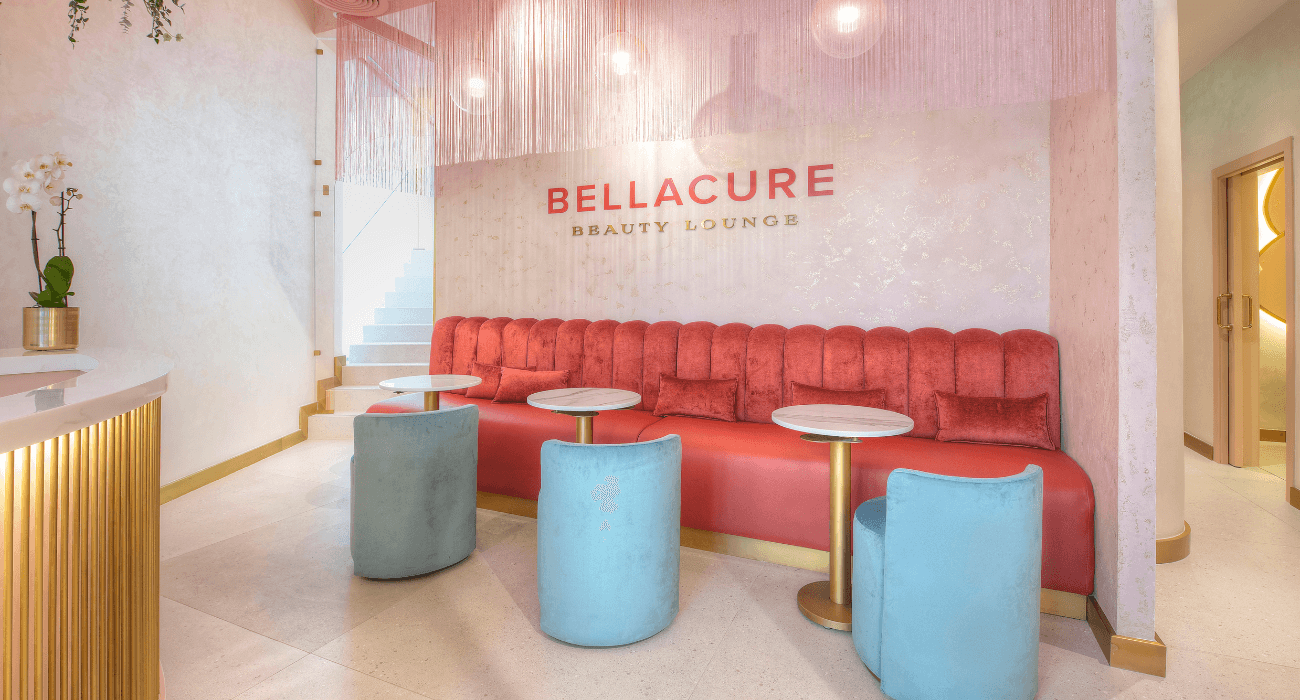 The lounge at Bellacure Sheikha Fatima Park: coral velvet banquette beneath the Bellacure sign